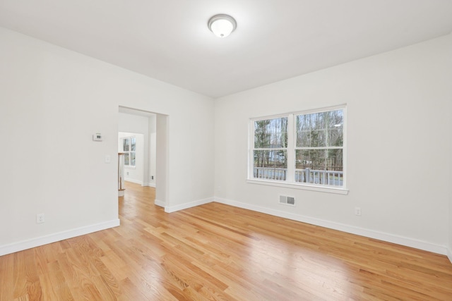 unfurnished room featuring visible vents, light wood-style flooring, and baseboards