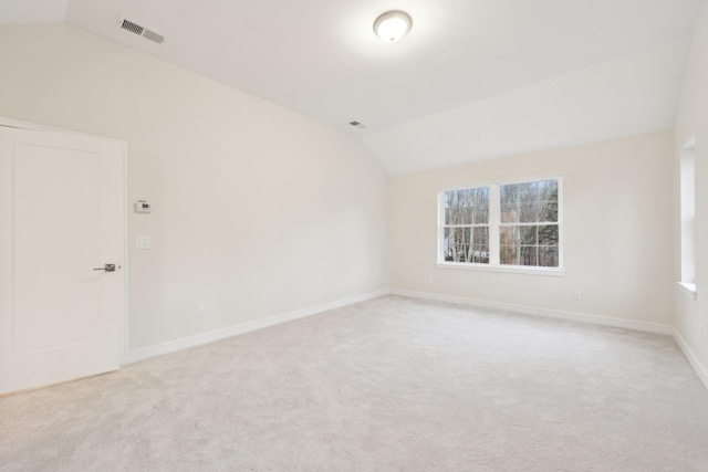 spare room featuring visible vents, vaulted ceiling, light carpet, and plenty of natural light