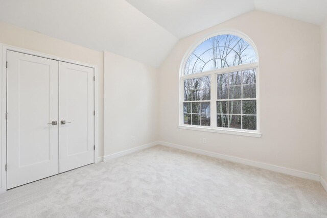 unfurnished bedroom featuring lofted ceiling, carpet, and baseboards