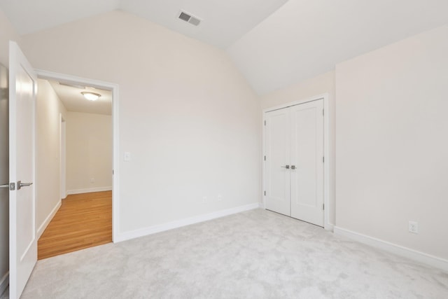 unfurnished bedroom with a closet, visible vents, vaulted ceiling, carpet, and baseboards
