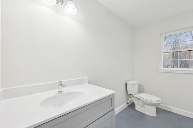 bathroom featuring toilet, tile patterned flooring, vanity, and baseboards