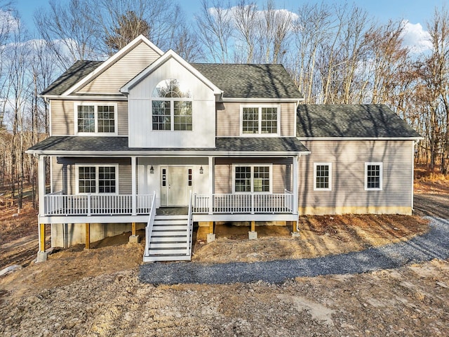 traditional-style home featuring stairway, covered porch, and roof with shingles