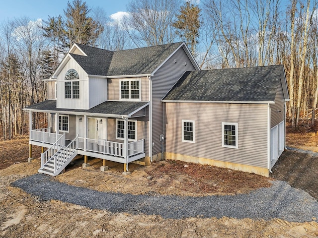 view of front of property featuring covered porch, a garage, and a shingled roof