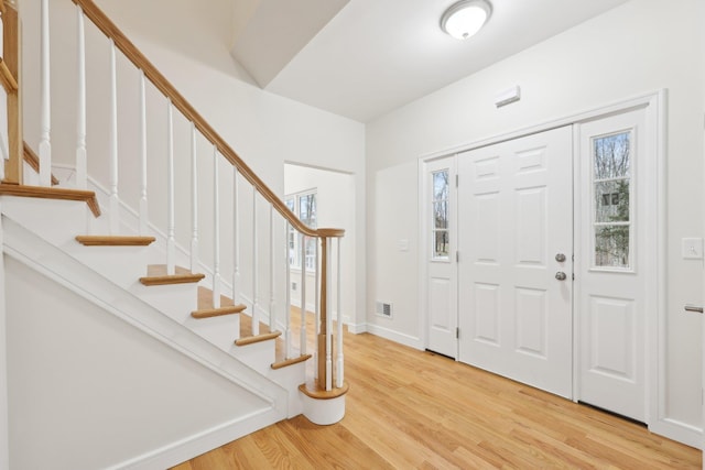 entryway with baseboards, visible vents, stairway, and light wood-style floors
