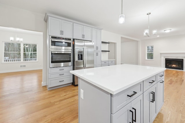kitchen with light wood-type flooring, an inviting chandelier, open floor plan, and appliances with stainless steel finishes