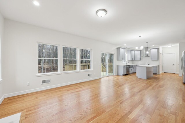 unfurnished living room featuring recessed lighting, light wood-style floors, a sink, baseboards, and visible vents