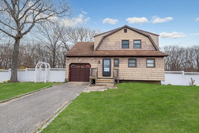 colonial inspired home featuring driveway, a front lawn, a garage, a gambrel roof, and fence