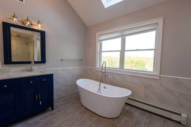 107 Denniston Dr, New Windsor, NY 12553 - bathroom featuring baseboard heating, tile walls, vaulted ceiling, a skylight, and a soaking tub