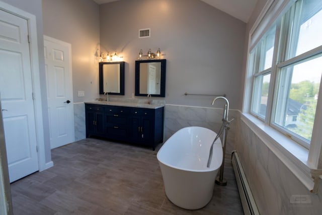 107 Denniston Dr, New Windsor, NY 12553 - bathroom with lofted ceiling, a baseboard radiator, tile walls, a freestanding bath, and double vanity
