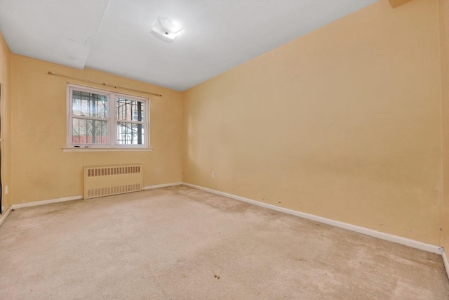 carpeted empty room featuring radiator heating unit and baseboards