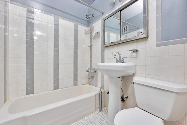 full bath with tile patterned floors,  shower combination, tile walls, and toilet