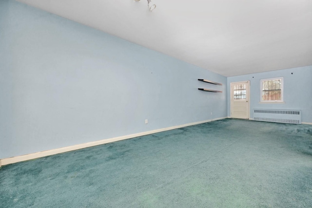 spare room featuring carpet flooring, baseboards, and radiator