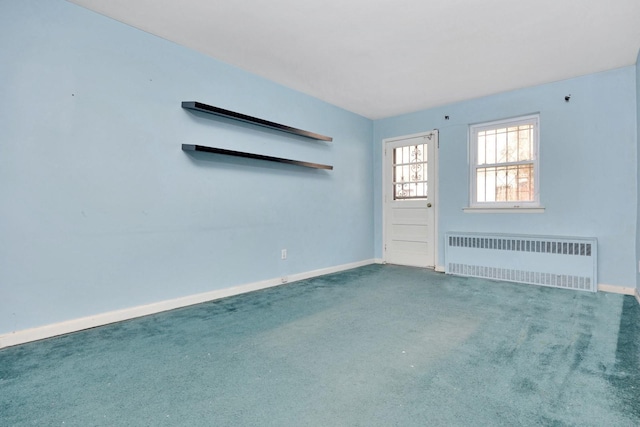 carpeted empty room with radiator heating unit and baseboards