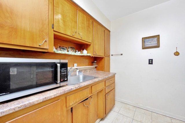 kitchen featuring open shelves, stainless steel microwave, light countertops, a sink, and baseboards