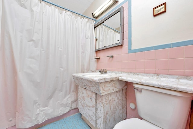 bathroom featuring toilet, tile walls, and vanity
