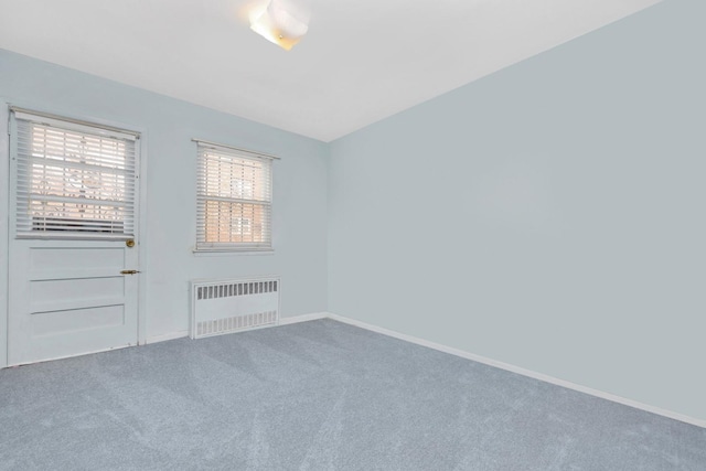 carpeted empty room featuring baseboards and radiator