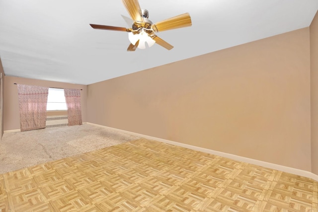 spare room with radiator, ceiling fan, and baseboards
