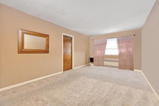 carpeted empty room featuring baseboards and radiator