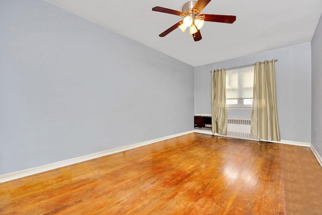 spare room with baseboards, a ceiling fan, wood-type flooring, radiator heating unit, and lofted ceiling
