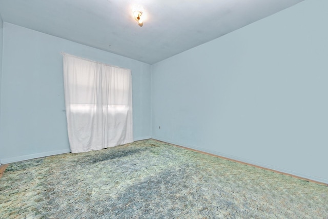 carpeted empty room featuring baseboards