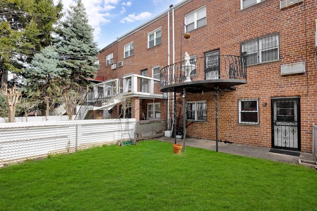 rear view of property featuring brick siding, fence, and a lawn