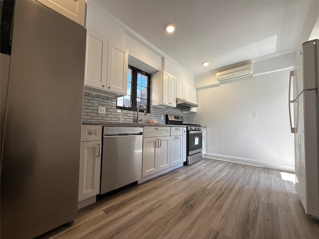 kitchen featuring ornamental molding, under cabinet range hood, stainless steel appliances, light wood finished floors, and backsplash