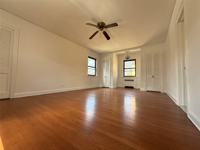 unfurnished room featuring ceiling fan, baseboards, and dark wood finished floors