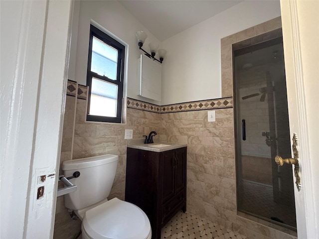 full bath with vanity, toilet, a shower stall, wainscoting, and tile walls