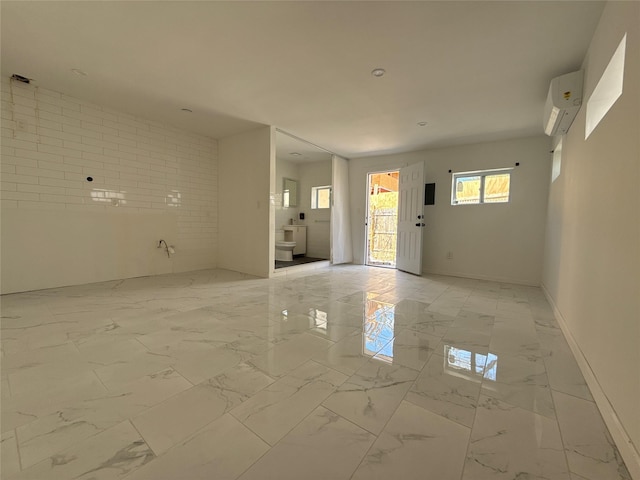 interior space featuring marble finish floor, baseboards, and a wall mounted air conditioner