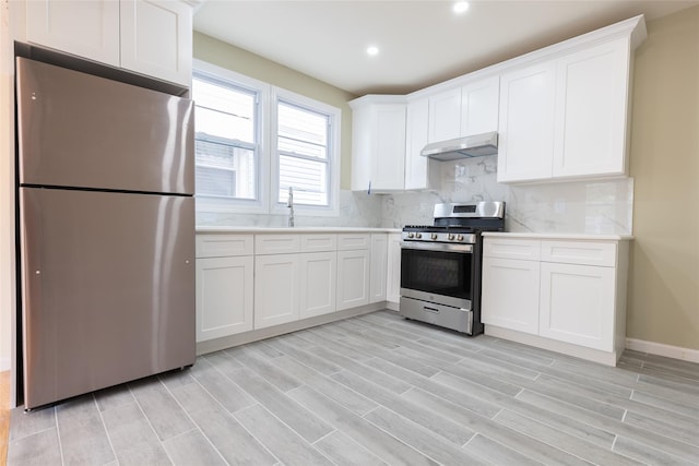 5933 48th Ave, Woodside, NY 11377 - kitchen with light countertops, backsplash, white cabinetry, under cabinet range hood, and appliances with stainless steel finishes