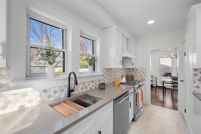 kitchen with a sink, light countertops, appliances with stainless steel finishes, white cabinetry, and backsplash