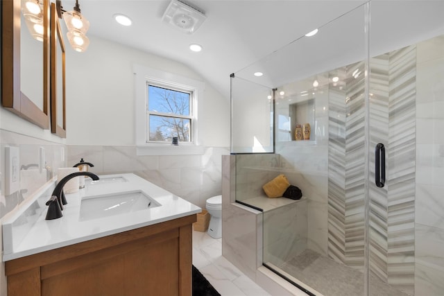 full bathroom with a sink, toilet, a tile shower, double vanity, and lofted ceiling