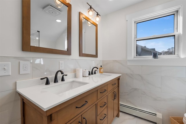 bathroom with tile walls, double vanity, a baseboard heating unit, and a sink
