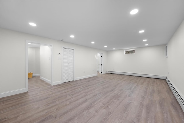 finished basement with recessed lighting, a baseboard heating unit, and wood finished floors