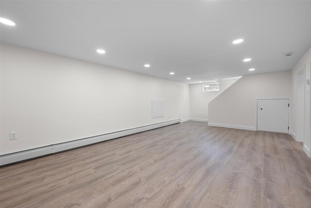 finished basement featuring baseboards, recessed lighting, a baseboard heating unit, and wood finished floors