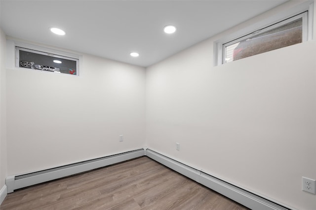 basement with recessed lighting, a baseboard heating unit, and wood finished floors