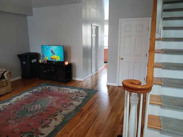 living room featuring stairway, baseboards, and wood finished floors