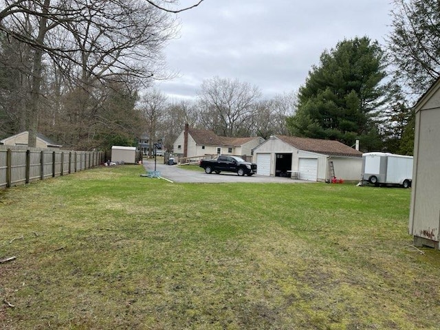 view of yard with a garage, fence, and an outbuilding