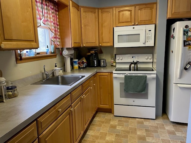 kitchen with a sink, light countertops, brown cabinetry, and white appliances
