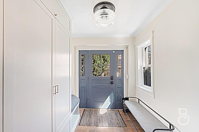 doorway to outside with crown molding and dark tile patterned flooring