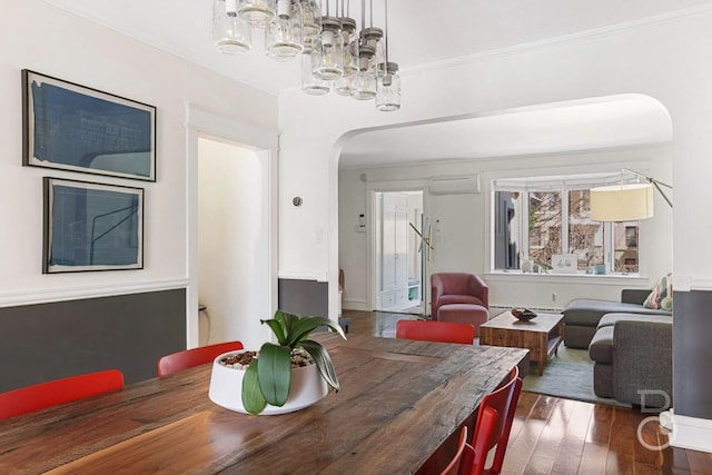 dining room with arched walkways, a notable chandelier, ornamental molding, and wood-type flooring