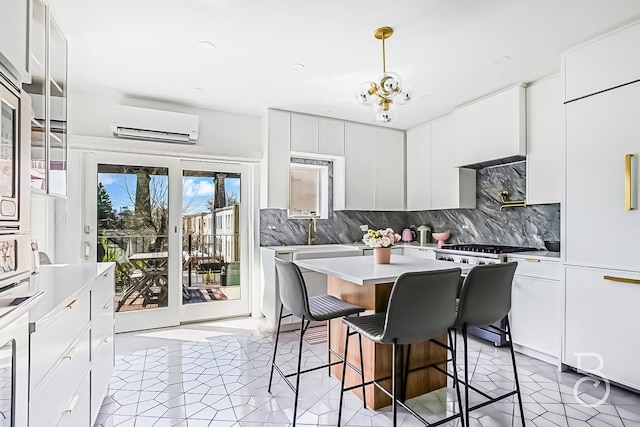 kitchen featuring backsplash, stainless steel range with gas cooktop, a wall mounted air conditioner, and a breakfast bar area
