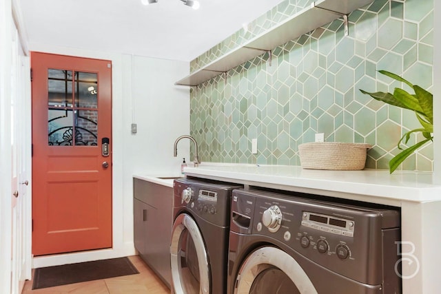 laundry area featuring washing machine and clothes dryer, a sink, laundry area, and light tile patterned floors