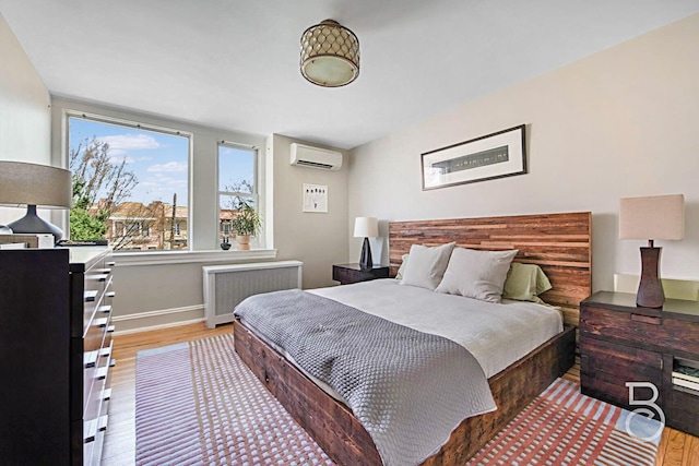 bedroom with baseboards, radiator heating unit, a wall mounted AC, and light wood-type flooring