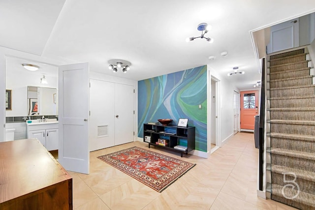 foyer with baseboards, visible vents, and stairway