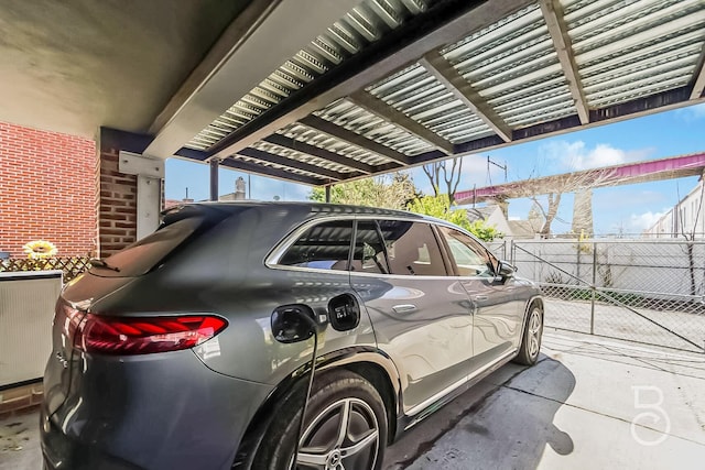 view of car parking with fence and a carport