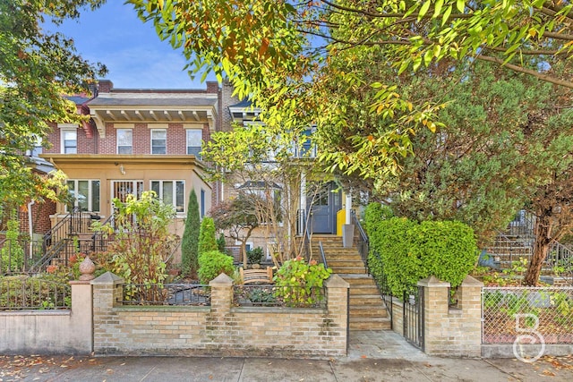 view of front of property with brick siding, stairs, and a fenced front yard