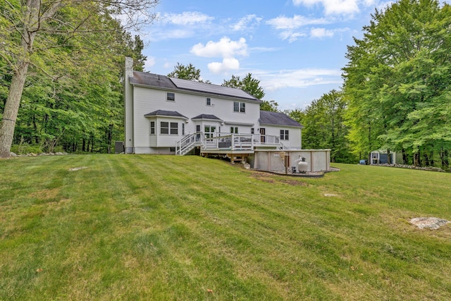 309 Quannacut Rd, Pine Bush, NY 12566 - rear view of house featuring a chimney, a lawn, a deck, and roof mounted solar panels
