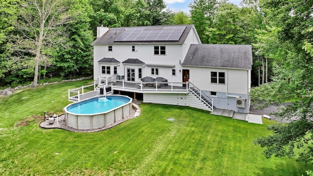 309 Quannacut Rd, Pine Bush, NY 12566 - rear view of property featuring a deck, a shingled roof, roof mounted solar panels, an outdoor pool, and a chimney