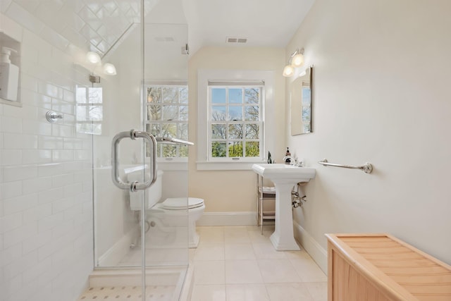 bathroom featuring toilet, baseboards, a shower stall, and tile patterned flooring